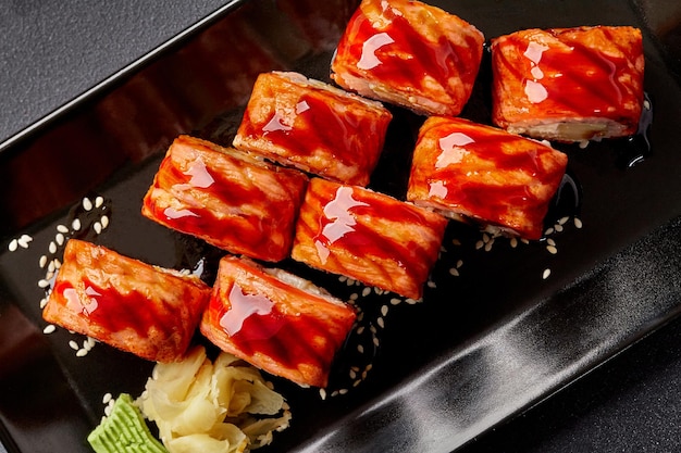 Foto involtini di sushi di salmone scottato con salsa unagi e sesamo serviti con zenzero sottaceto e wasabi