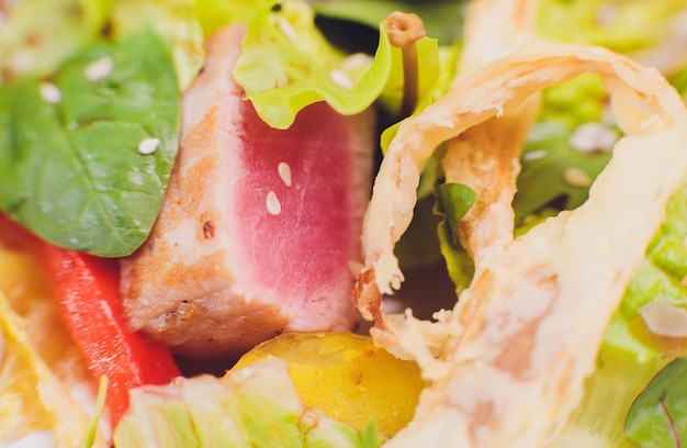 Seared tuna coated sesame seeds with green salad on white plate