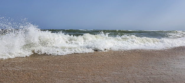 Seascape. Azure color of water, waves foaming on the shore. Selective focus.