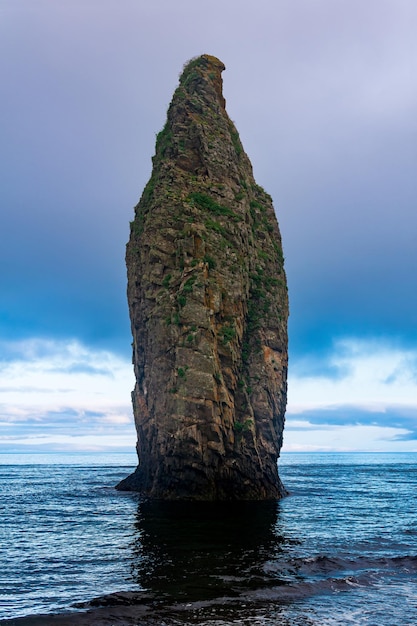 Seascape of Kunashir ocean shore with a huge vertical rock in the water