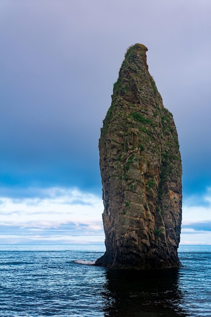 Seascape of Kunashir ocean shore with a huge vertical rock in the water