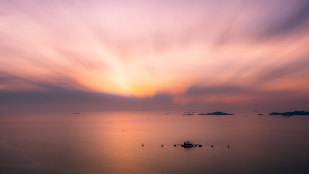 夕暮れと中海の小さな石油タンクターミナルでの海景自然シーンとモーションブラープロセス背景の壁紙コンセプト写真ドローンからの空中写真