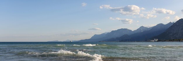 Морской пейзаж и галечный пляж с волнами в теплом летнем дне белой пены на море