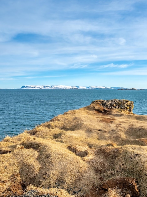 Seascape view with moutain under cloudy blue sky from Stykissholmur lighthouse hill in Iceland