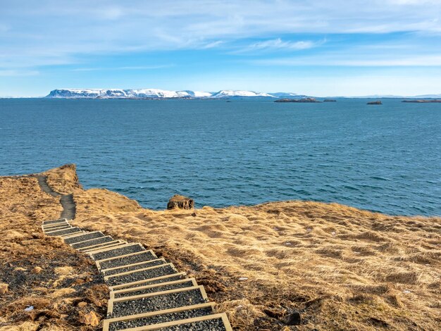 Seascape view with moutain under cloudy blue sky from Stykissholmur lighthouse hill in Iceland