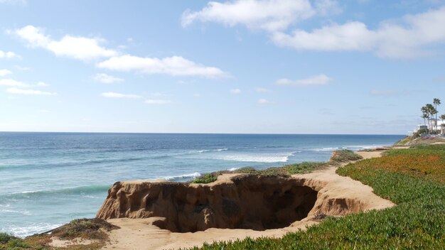 海景の眺望ポイント、米国カリフォルニア州カールスバッドの視点。パノラマの海の潮、青い海の波、急な侵食された崖の上から。海岸線の海岸線を見落とす。緑の氷の植物の多肉植物の芝生。