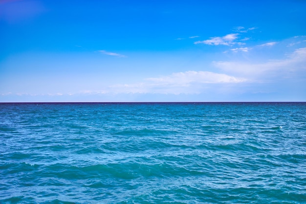 Seascape with clear horizon line and clouds on blue sky travel background and banner ocean waves