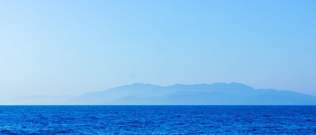 霧と山々の海景。日没時の海景。もやの中の海から山への眺め