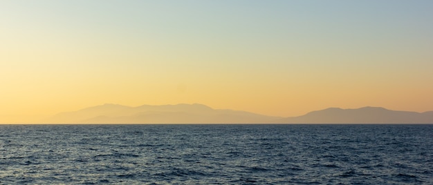 霧と山々の海景。日没時の海景。もやの中の海から山への眺め