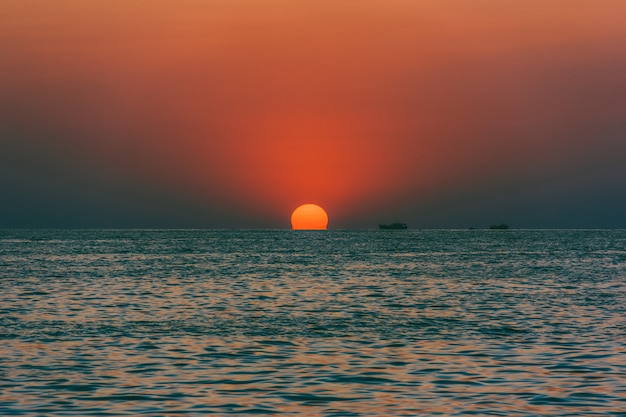 Vista sul mare con il sole al tramonto e le navi