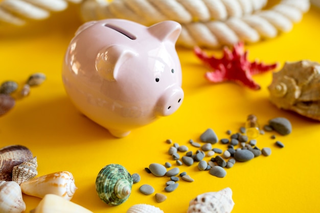 Seashells, pebbles and piggy bank on a yellow background.  