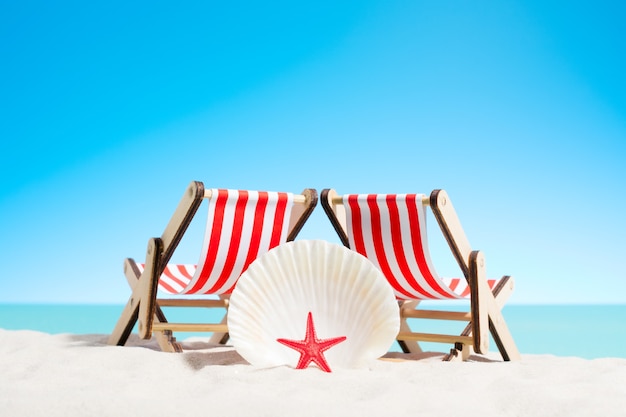 Seashells and two sunbeds at the beach, sky with copy space