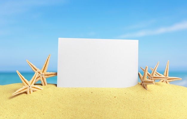 Seashells with blank card on sand beach