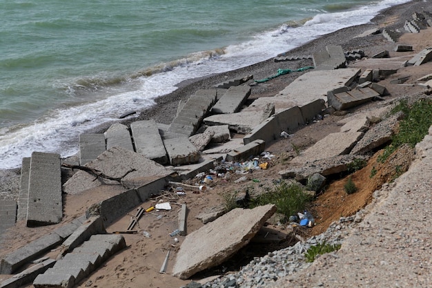 Seashore destruction after storm. Destroyed concrete structures and staircases. Plastic garbage.