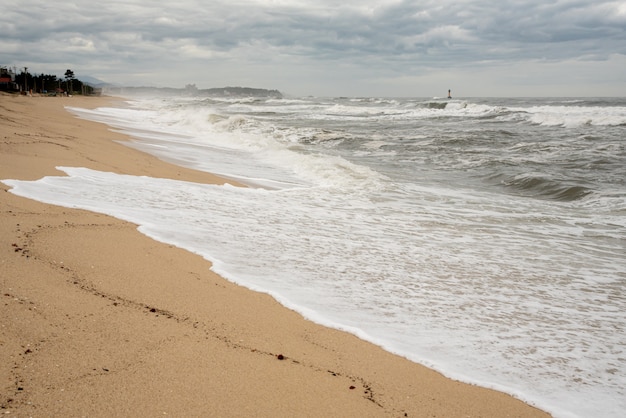 A seashore scene in which high waves come with cloudy weather and strong winds. 