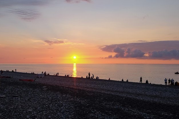 夕暮れの海辺遠くの人々