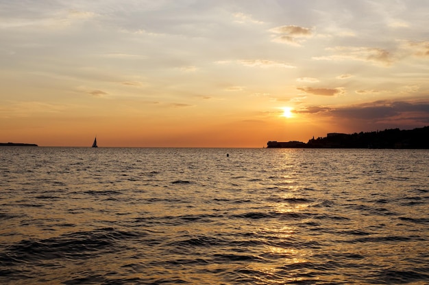 スロベニアの海岸にある海辺のリゾートタウン。夏のオレンジ色の夕焼け空。木製の桟橋への風光明媚なビュー。海