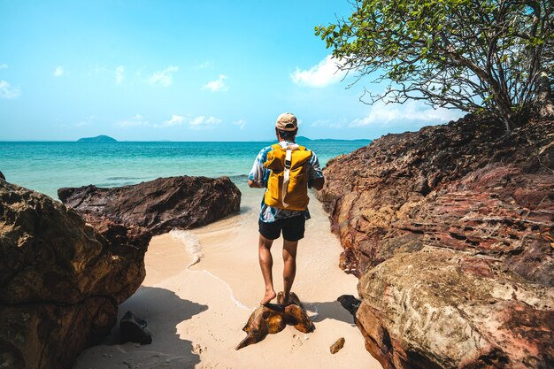 黄色いバッグを持った海辺の旅行者がビーチに旅行する