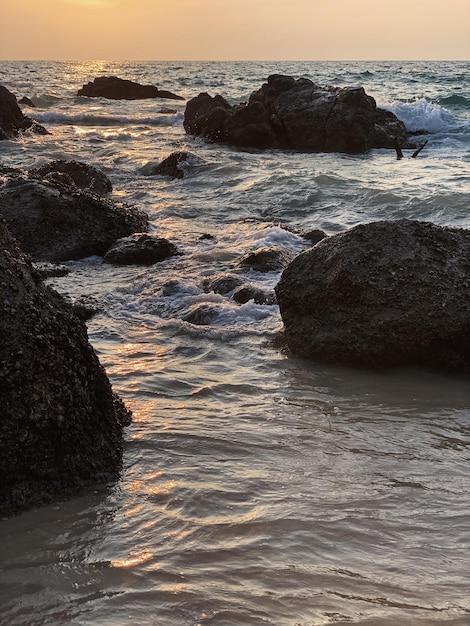 岩や波と夕日や日の出の海辺の景色
