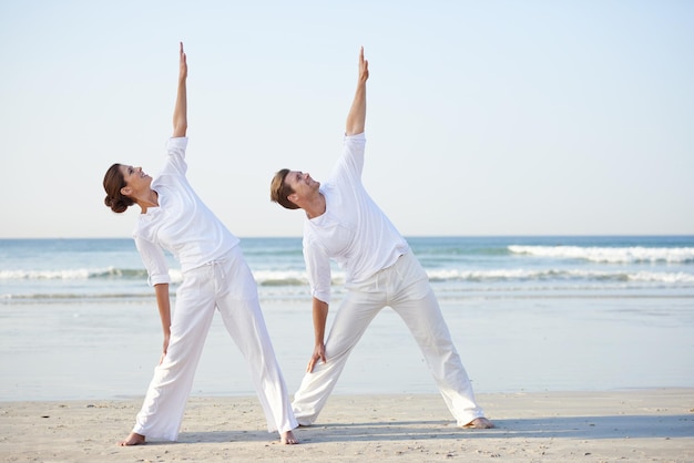 Seaside yoga A young couple practising yoga on the beach