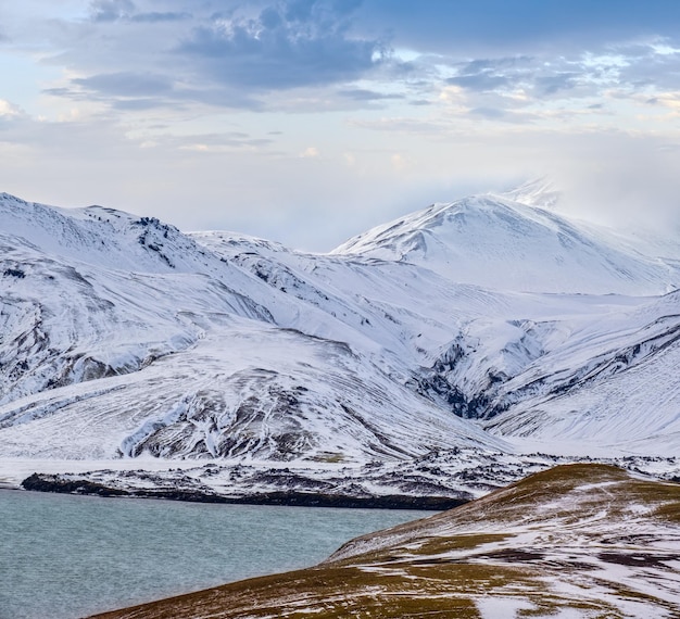 Photo season changing in southern highlands of iceland colorful landmannalaugar mountains under snow cover in autumn frostastadavatn lake at the foot of the mountains