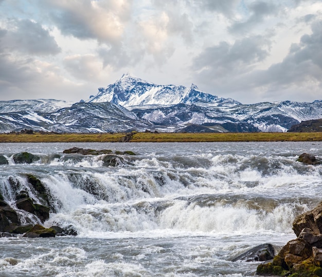 Season changing in southern Highlands of Iceland Picturesque waterfal Tungnaarfellsfoss panoramic autumn view Landmannalaugar mountains under snow cover in far