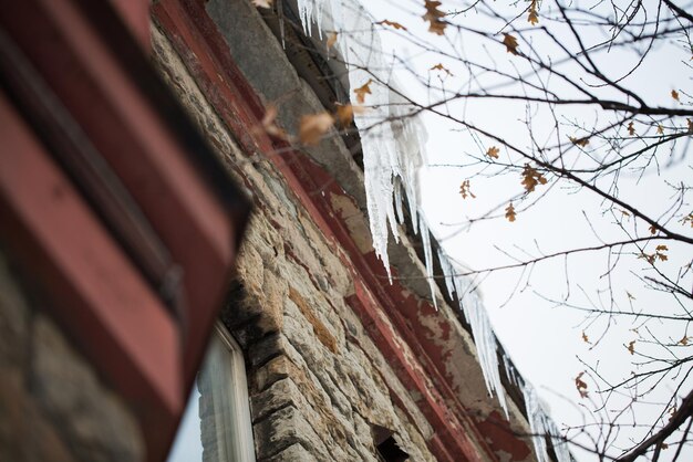 Foto concetto di stagione, alloggio e inverno - ghiaccioli appesi al tetto dell'edificio