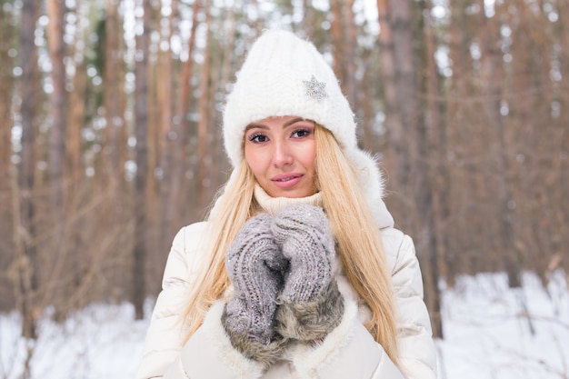 Season and people concept - Attractive blond woman dressed in white coat and white hat standing in