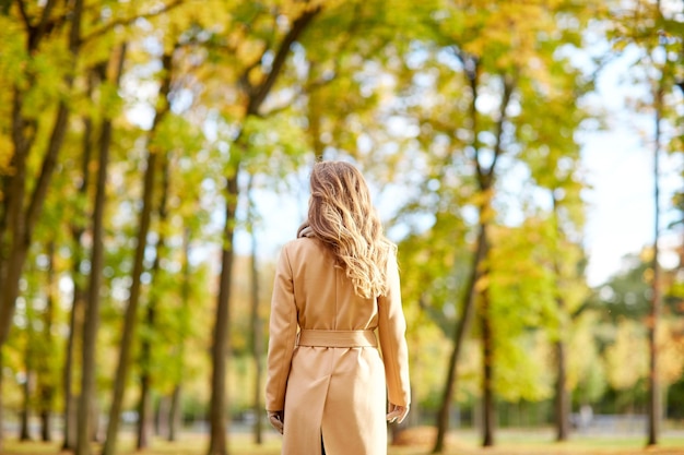 season and people concept - beautiful young woman walking in autumn park