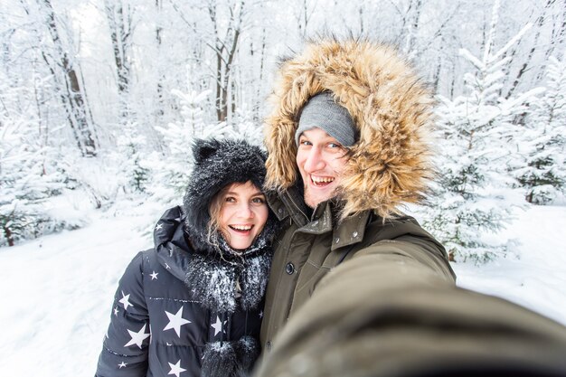 Season and relationship concept - Funny couple taking selfie in the winter time