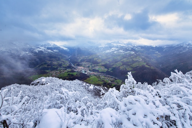 木々の雪との季節のコントラストは、牧草地のある低い谷の村を垣間見る