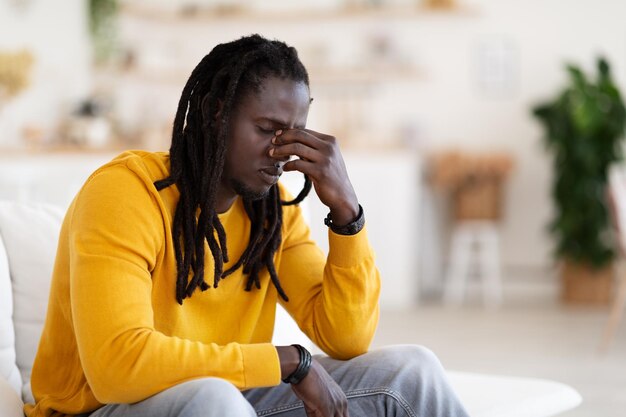 Seasonal depression concept upset african american male sitting alone at home