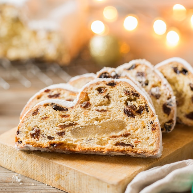 Seasonal food and drink, winter concept. Traditional European German homemade Christmas cake, pastry dessert Stollen on a wooden backgrounds with festive decoration.