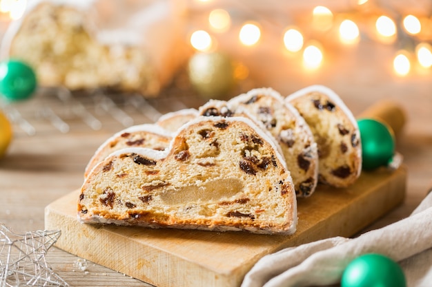 Seasonal food and drink, winter concept. Traditional European German homemade Christmas cake, pastry dessert Stollen on a wooden backgrounds with festive decoration.