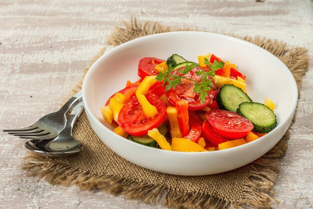Seasonal fresh vegetable salad. Ripe tomatoes, cucumbers, bell peppers. Healthy food concept. Wooden background, copy space