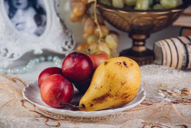 Photo seasonal fruits pears and plums in a rustic plate.