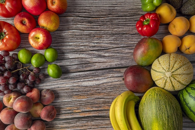 Сезонные фрукты и овощи на деревянной доске Красные яблоки персики и парагвайцы красные лаймы и виноград бананы и дыни помидоры и арбузы