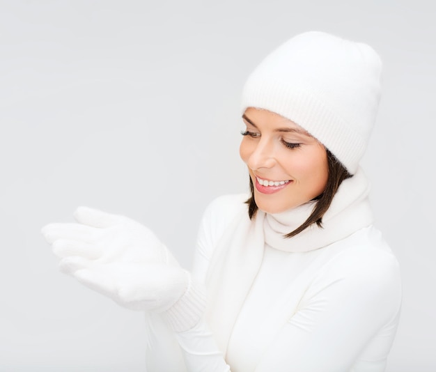 seasonal, people, happiness concept - smiling woman in winter clothes with something on palms