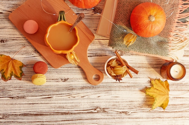 Seasonal pumpkin latte in shape of pumpkin cup among desserts and leaves Lagom cozy home