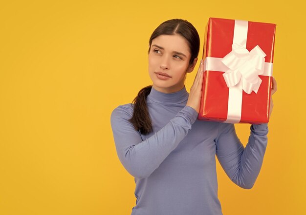 Seasonal sales curious girl with box on yellow background boxing day present and gifts buy