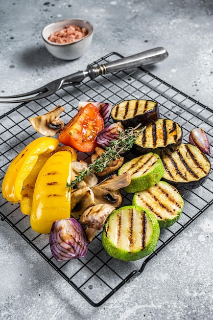 Estate stagionale verdure grigliate su griglia peperone zucchine melanzane cipolla e pomodoro sfondo grigio vista dall'alto