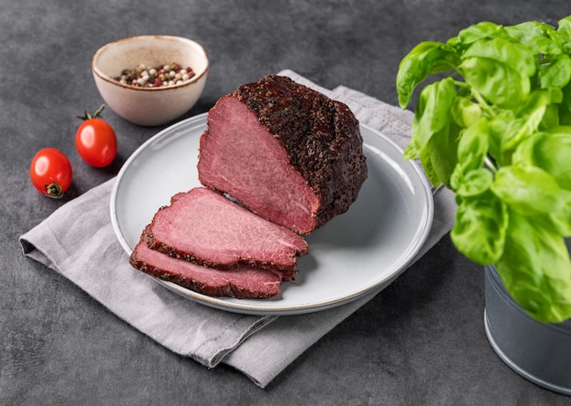 신선한 채소와 허브와 함께 어두운 배경에 접시에 조각으로 맛있는 연기 된 고기 자연 고기 간식
