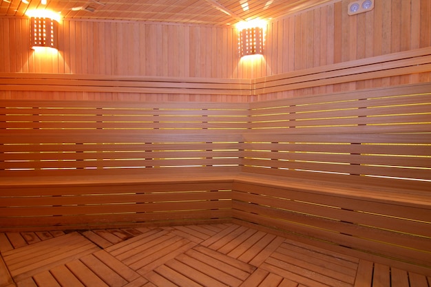 Seat in sauna room Empty wooden steam room with stone heaterSauna room for good health