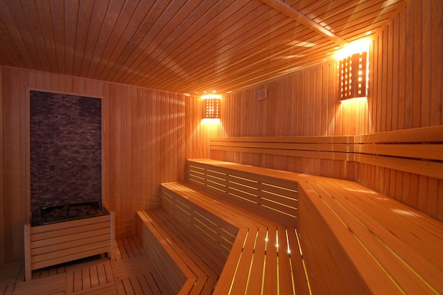 Seat in sauna room Empty wooden steam room with stone heaterSauna room for good health