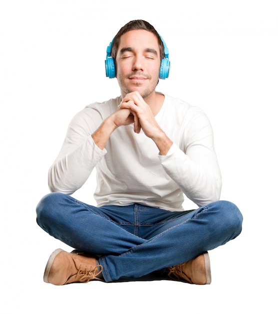 Photo seated happy young man using a headphones