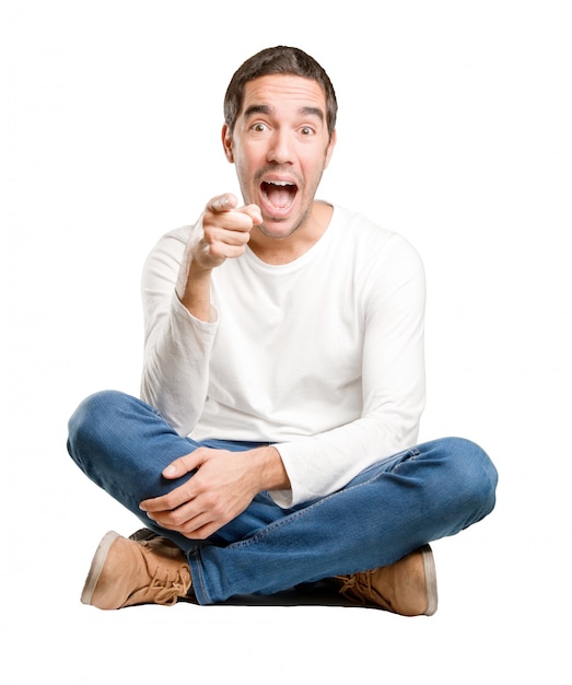 Seated young man laughing and pointing you