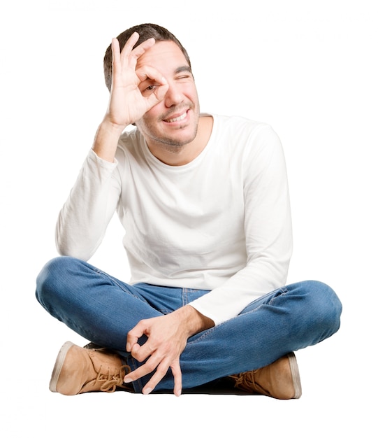 Seated young man with an observe gesture