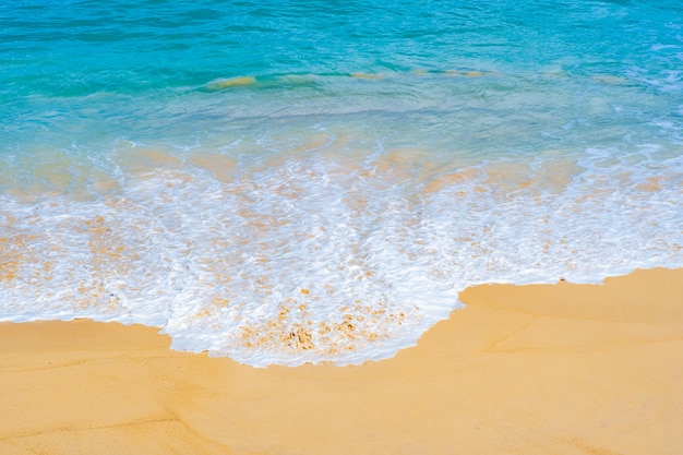 Spruzzata delle onde dell'acqua di mare sulla spiaggia sabbiosa