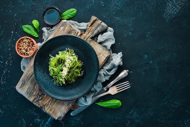 Seaweed salad in a black plate Chuka wakame On the old background Top view Free space for your text