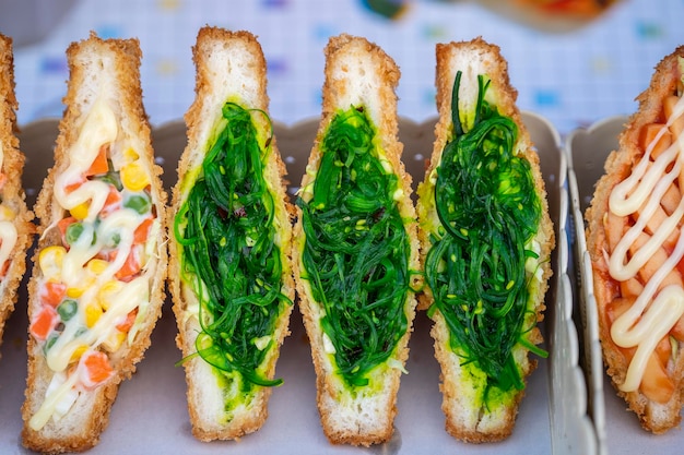 태국의 길거리 음식 시장에서 판매되는 해초 샐러드 샌드위치 맛있는 녹색 해초 샐러드 샌드위치를 닫습니다.